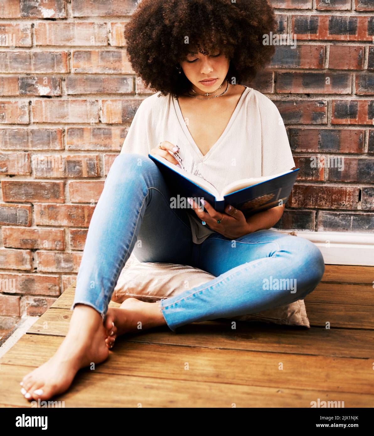 Woman reading books, story and study at home for relaxed learning, studying and education. College student, young black person on ground and Stock Photo