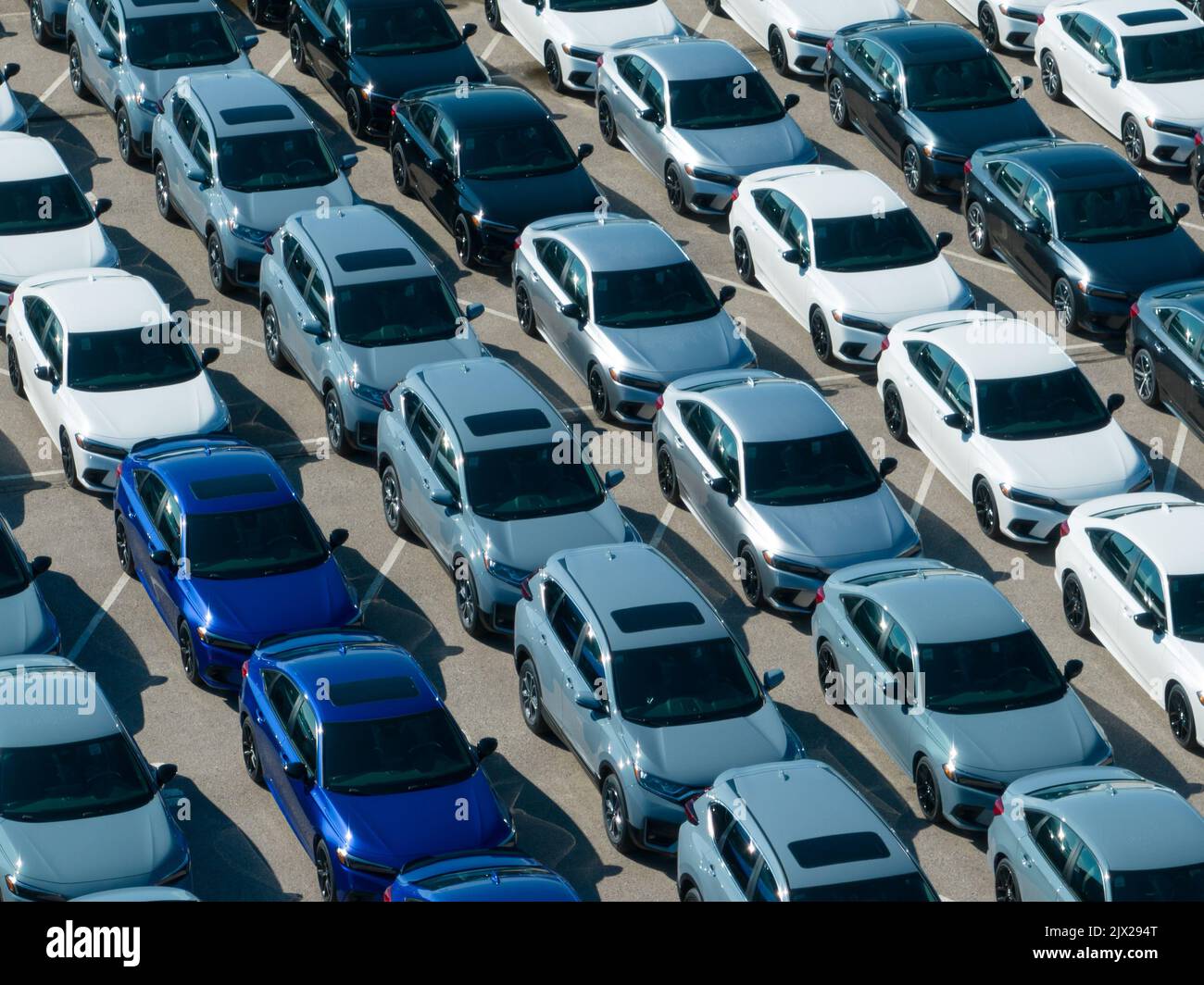 An aerial view above a parking lot at a Honda Motor Company plant. Rows of newly manufactured Honda Civic and CR-V vehicles, seen on a sunny day. Stock Photo