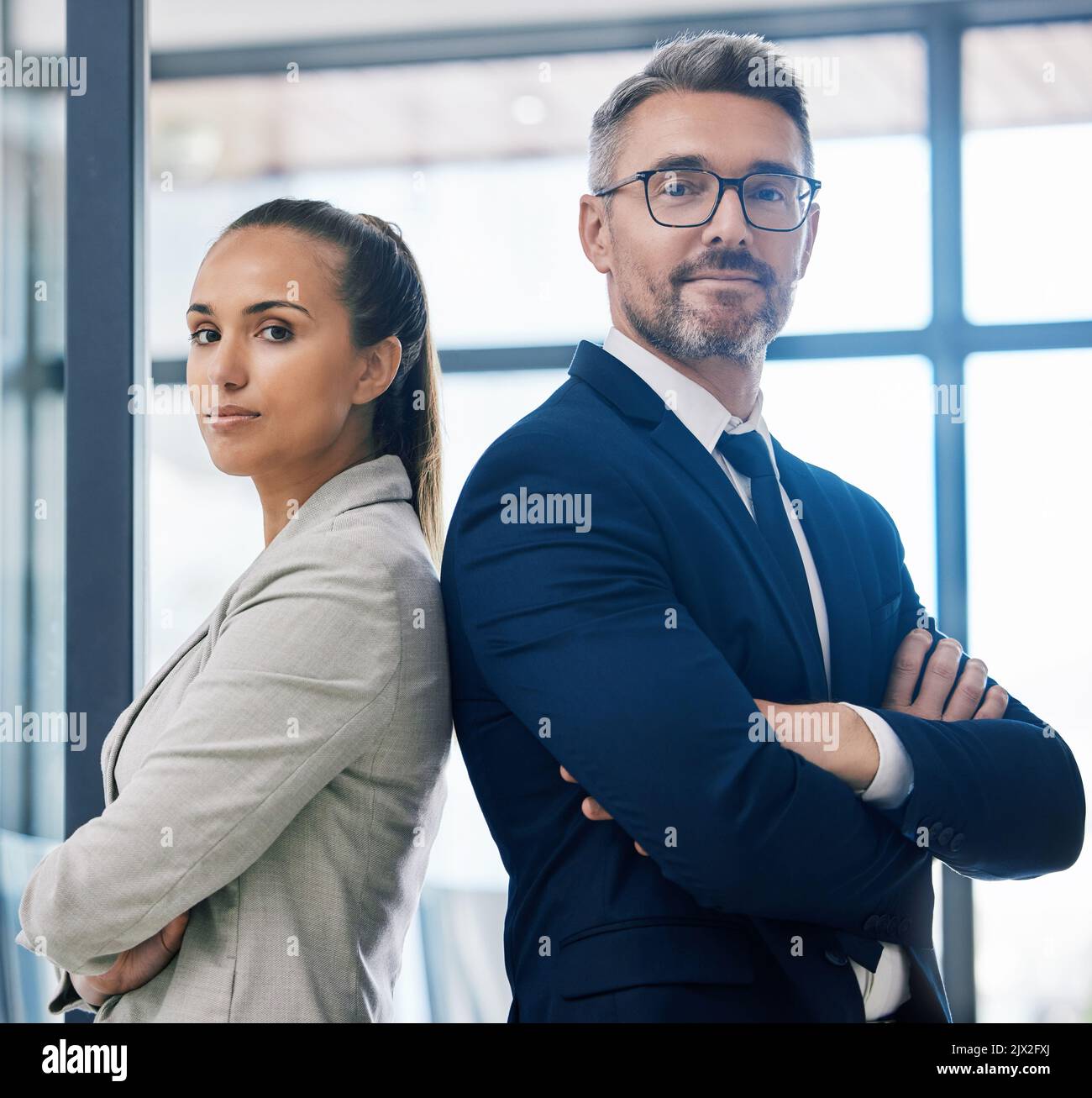 Partnership, arms crossed and teamwork with two business people standing together in corporate office building. Success, motivation and vision with Stock Photo