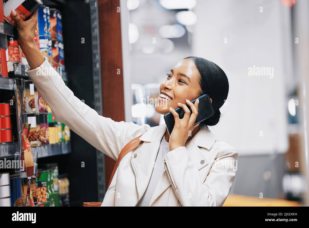Happy supermarket, grocery shopping and customer with 5g phone, smile and in retail store for food, groceries or product from shelf. Woman with Stock Photo