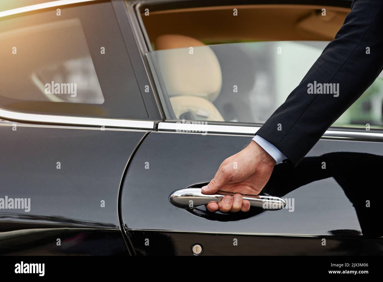 Allow me...an unrecognizable male chauffeur opening a car door. Stock Photo