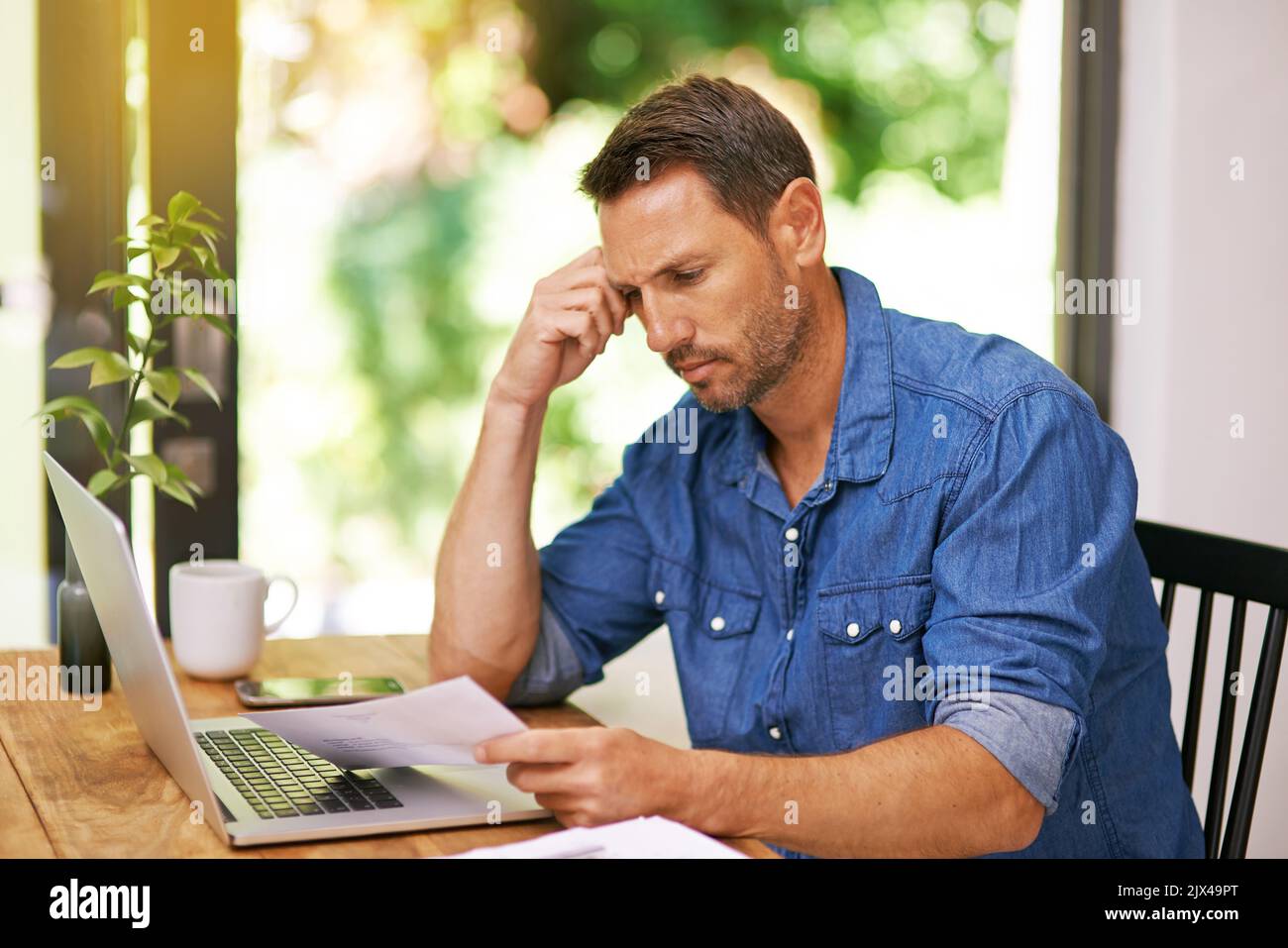 Admin day...a man looking over some paperwork while working from home ...