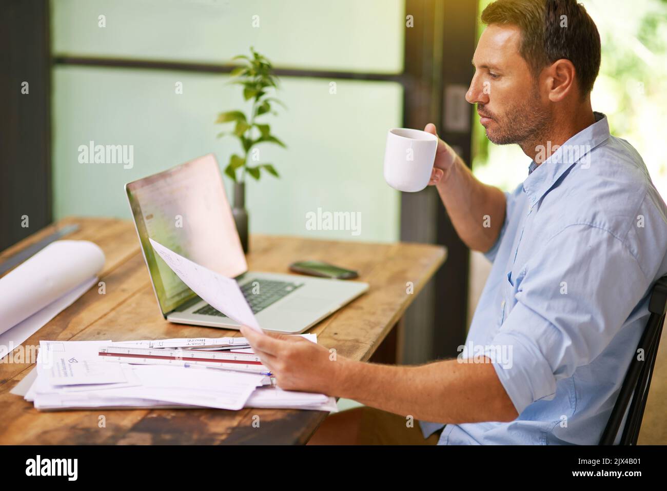 Proof reading the contract in the company of coffee. a young man working from home. Stock Photo