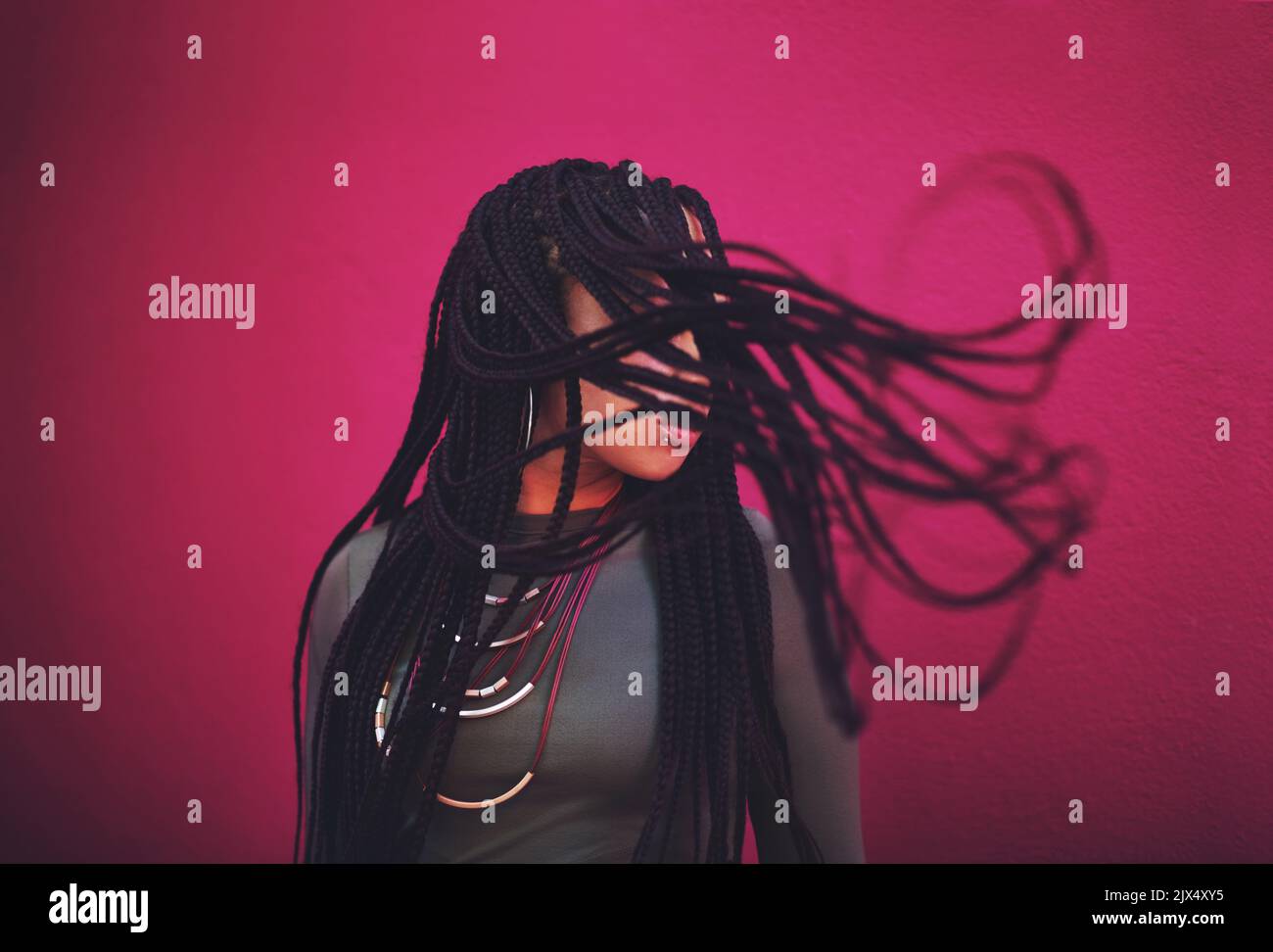 Shes rocking that hairstyle. a young woman with braids posing against a 
