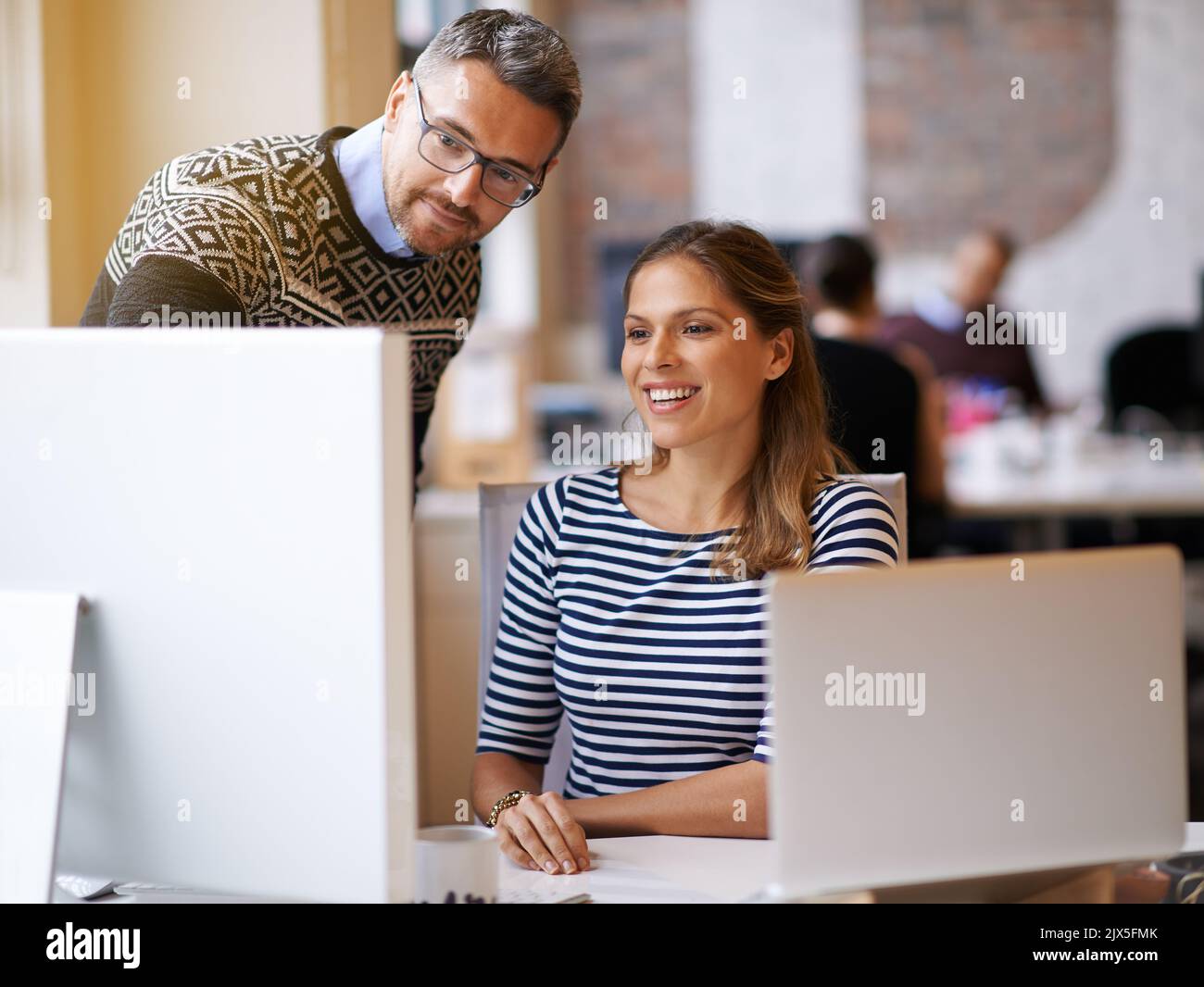 Playing around with different designs. two designers working together at a computer. Stock Photo