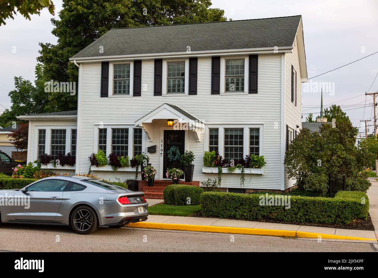 A silver Ford Mustang parked in front of a white home in Auburn