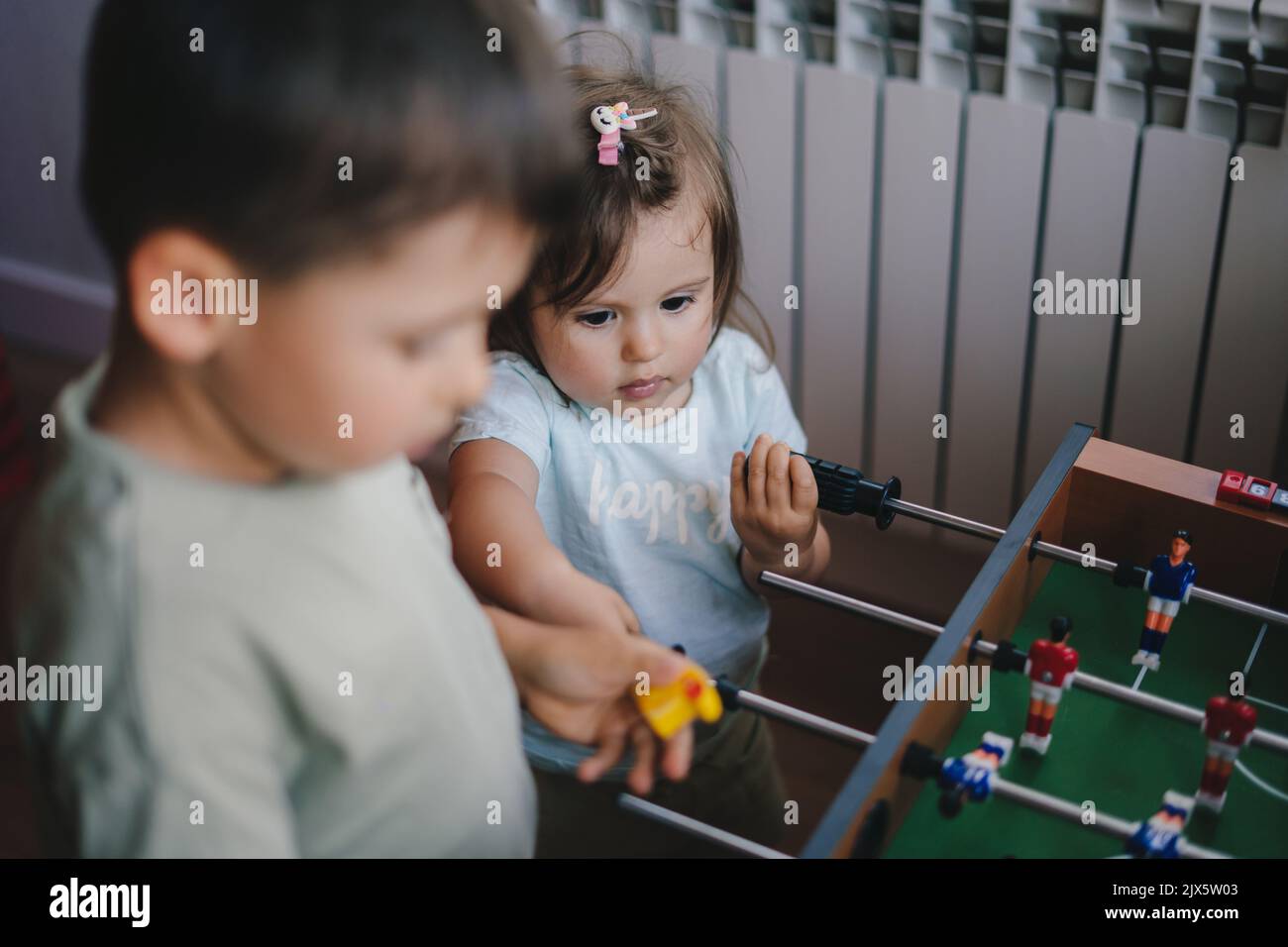 Two little kids learning by playing the wooden table football