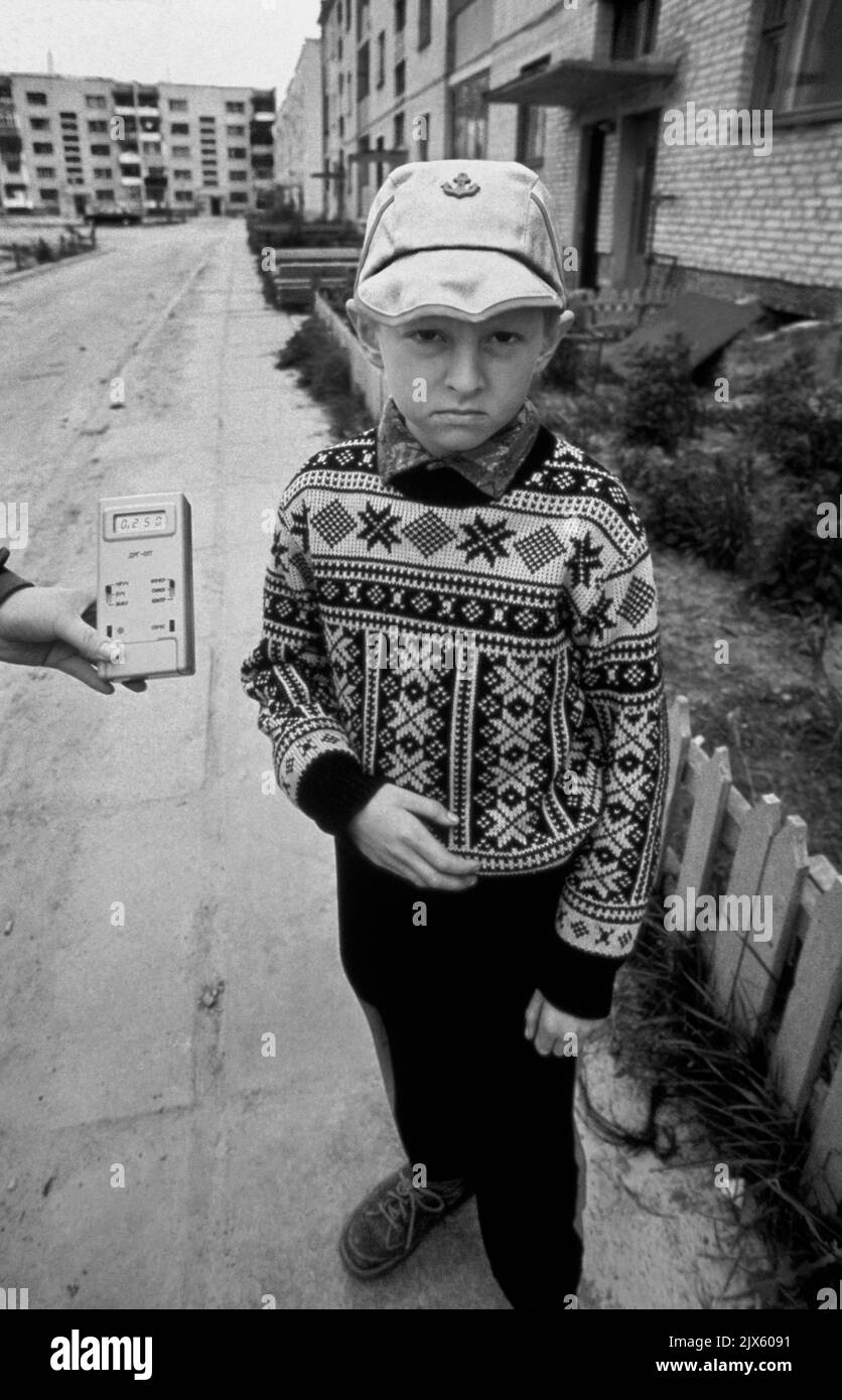 Bragin, Belarus, 15 May 1990. A medical technician holds a Geiger counter next to a young school boy standing outside the four story soviet Apartment block that he lives in.  The counter shows a radiation reading more than ten times higher than normal, four years after the 1986 accident at Chernobyl Nuclear Power Plant in the Ukraine, about 50 miles (80km) away. Stock Photo