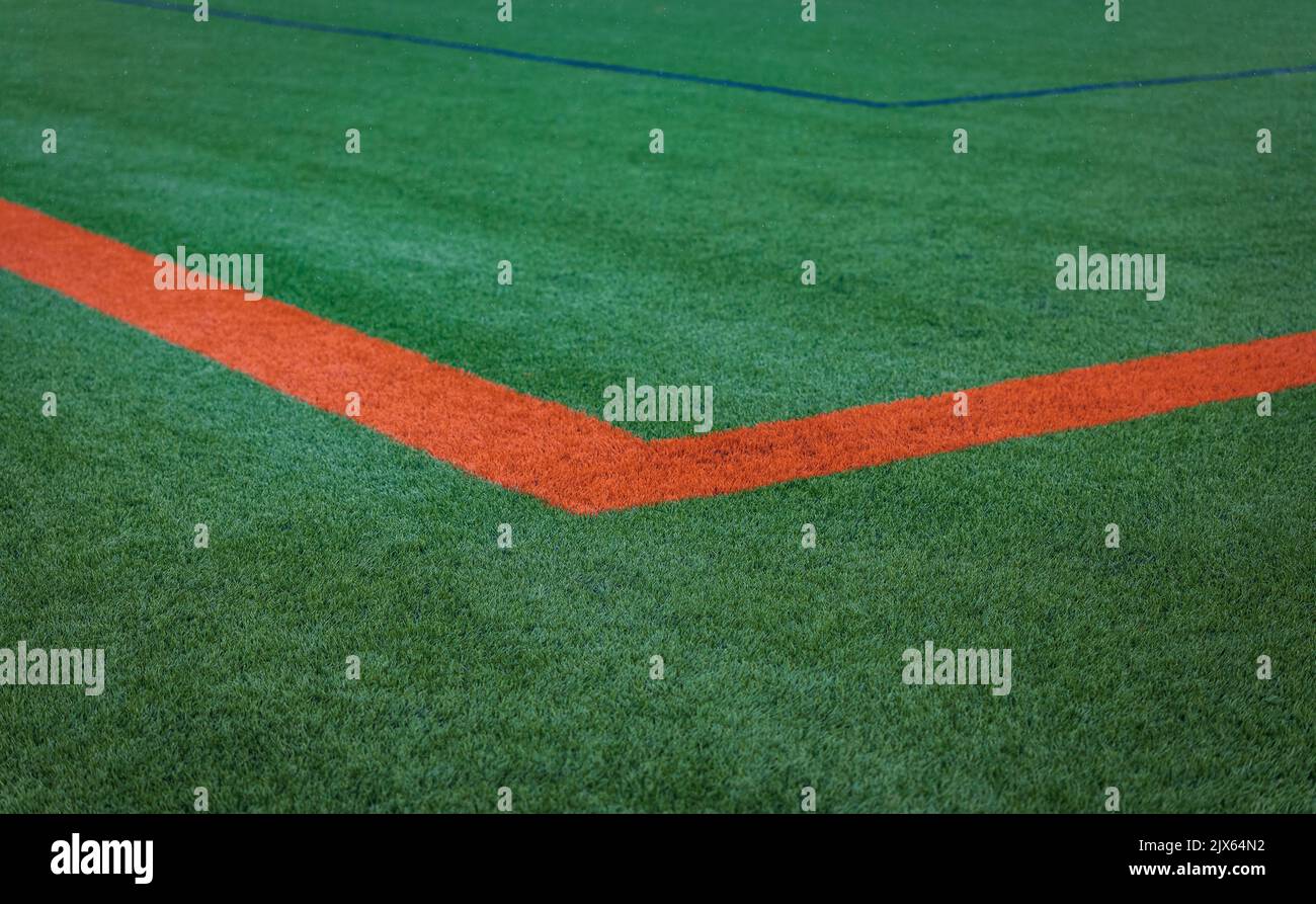 Orange stripe on the green soccer field from top view. Green empty