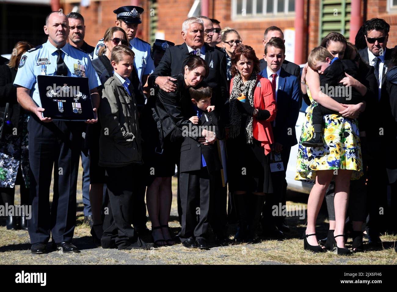Senior Constable Brett Forte's family (R to L) stepdaughter Emma holding  son Sam, his parents Heather and Stuart and wife Susan hugging son Brodie,  watch as his casket is being put in