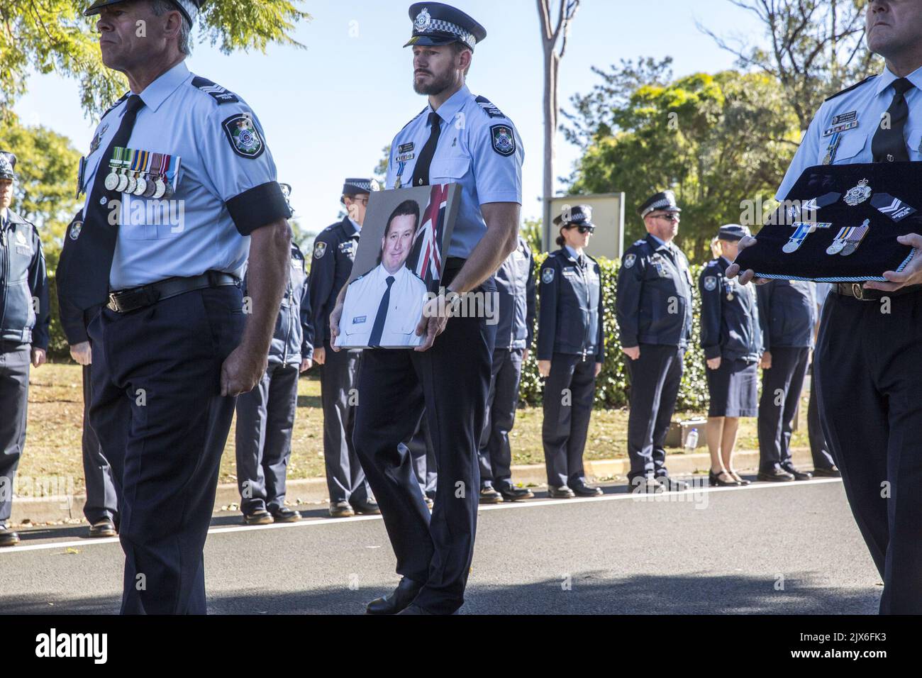 Sergeant Glen Thomas carries a photograph of Senior Constable Brett Forte  during the funeral procession in Toowoomba, Wednesday, June 7, 2017. Senior  Constable Forte was killed on May 29 near Gatton, when