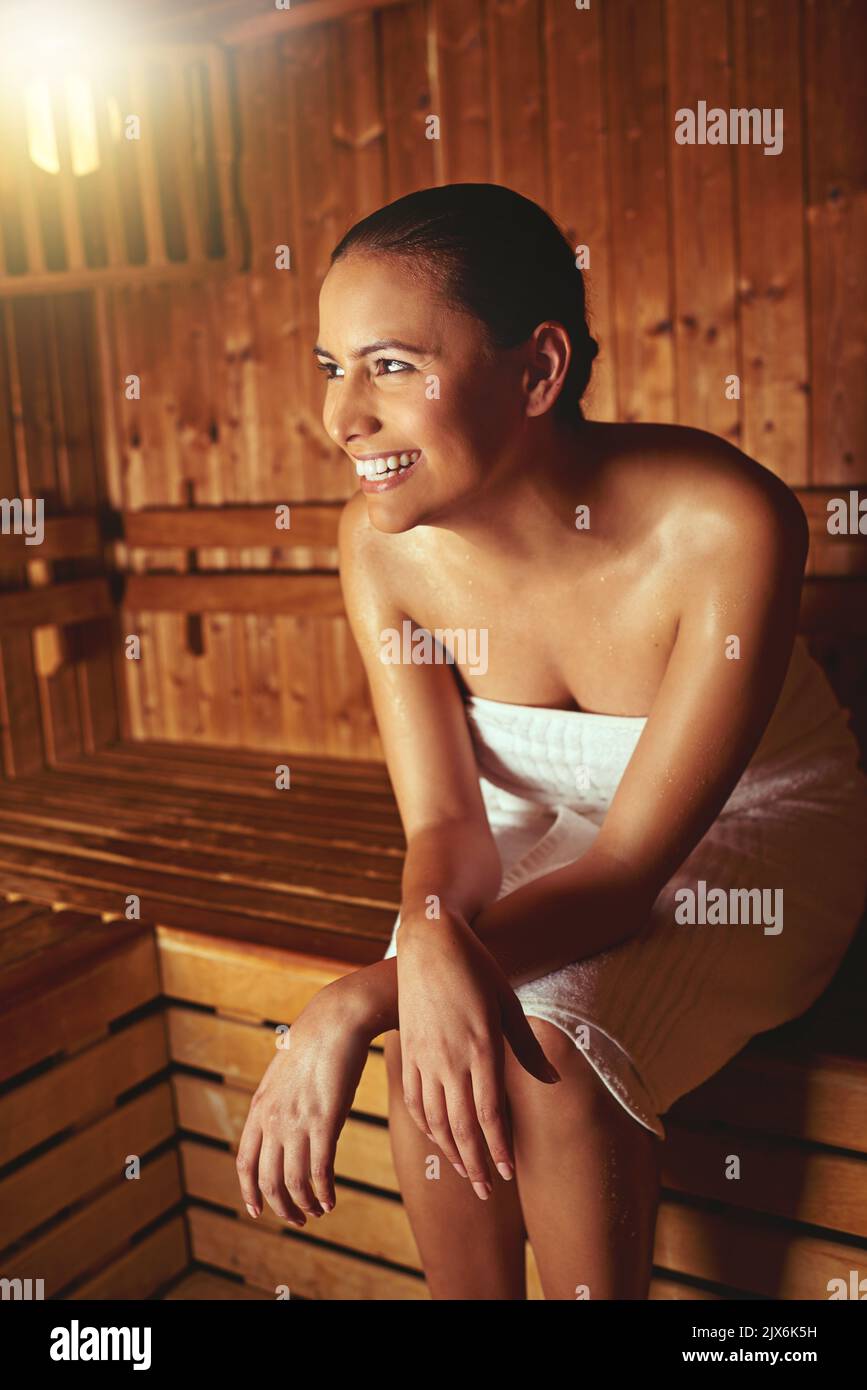 She couldnt think of any place shed rather be. a young woman relaxing in the sauna at a spa. Stock Photo