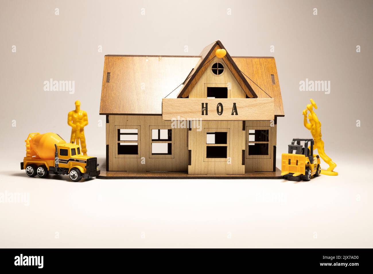 The word HOA is written on the wooden surface. Workers working on wooden miniature house in the background. business and finance Stock Photo