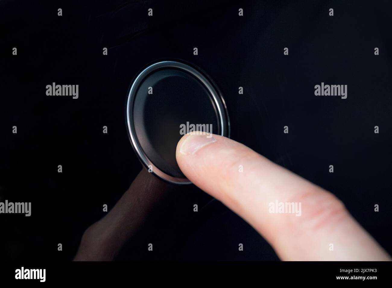 White index finger pressing a small black button Stock Photo