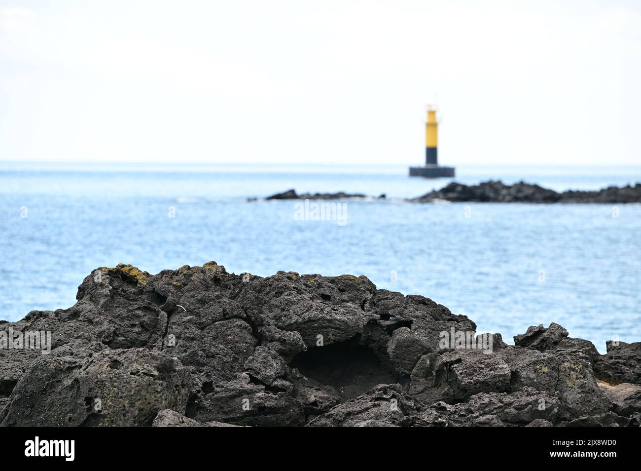 You can see the rocks on the beach and the lighthouse behind them Stock Photo