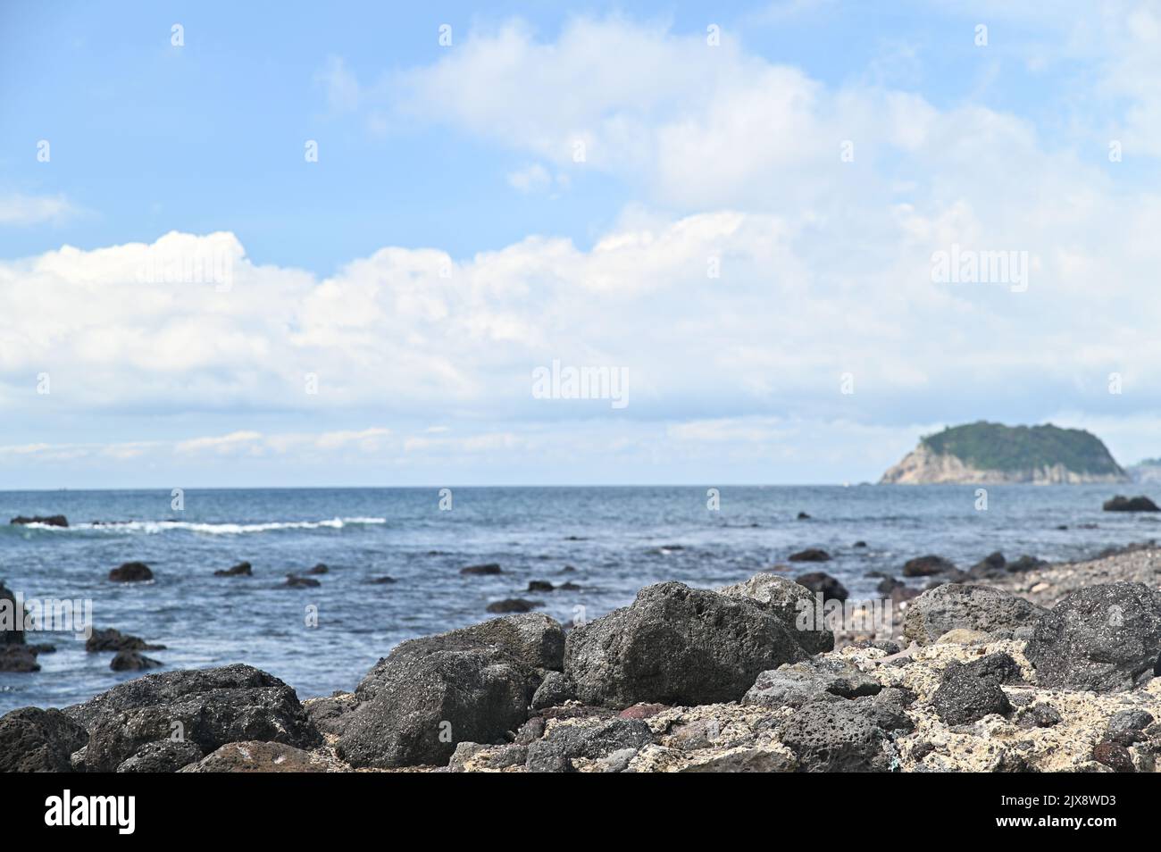 There are rocks and after that we can see the sea and island Stock Photo