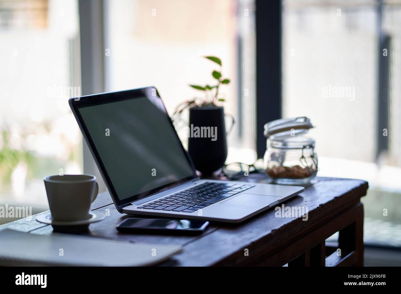 workspace of a freelancer working from home with laptop and cellphone on end table Stock Photo