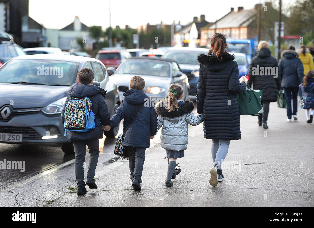File photo dated 17/01/20 of parents walking their children to school in Hornchurch, Essex, past stationary cars, as eight out of 10 people who responded to a survey about car idling said they want it banned outside school gates. Stock Photo