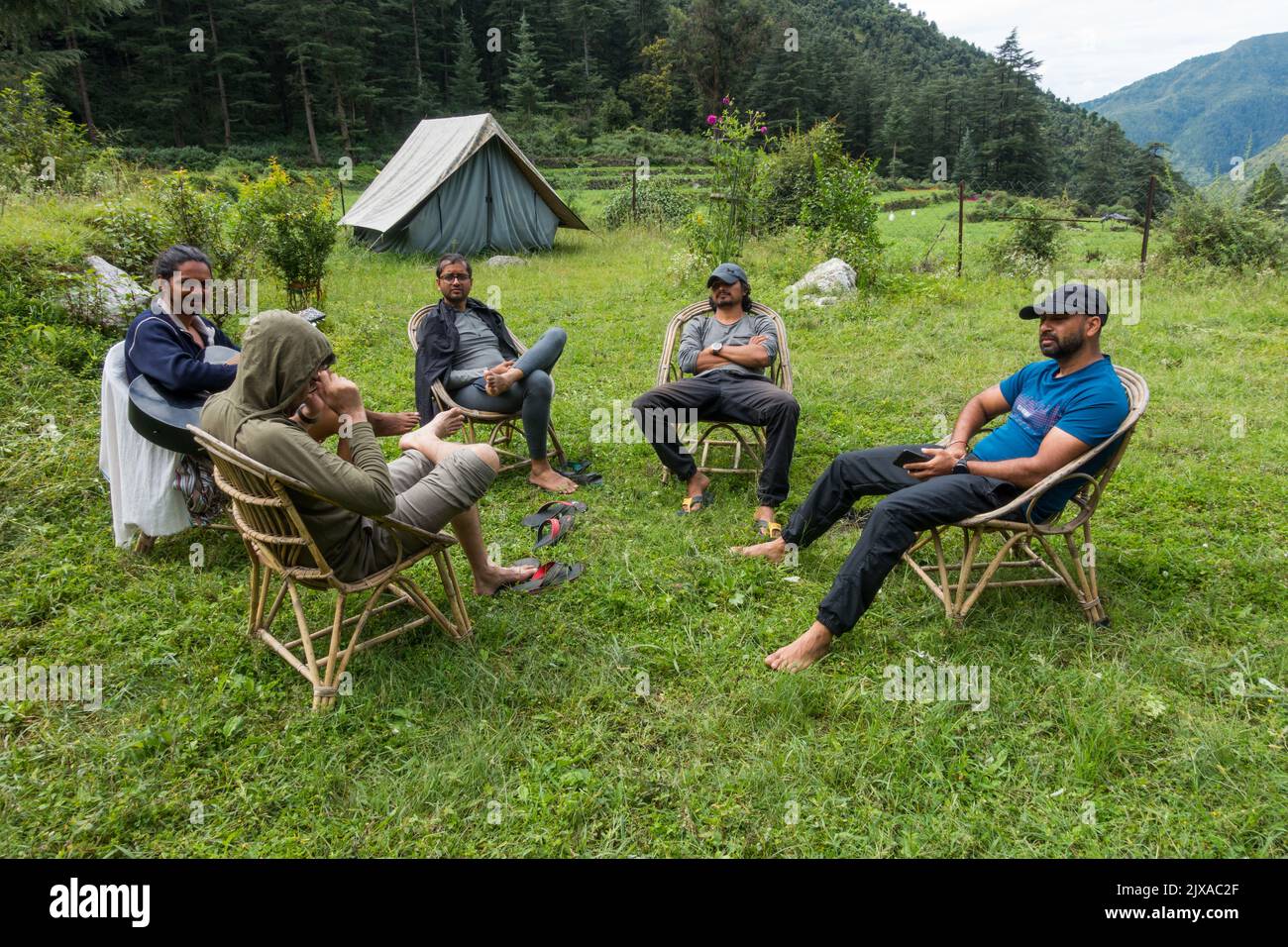 September 17th 2021 Himalayas Uttarakhand India. A group of campers relaxing together on a campsite surrounded with mountains and deodar forest. Stock Photo