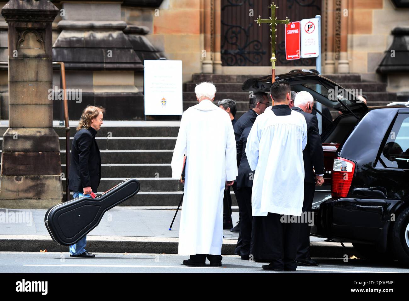 Angus Young waits to place a guitar in the hearse as they load the ...