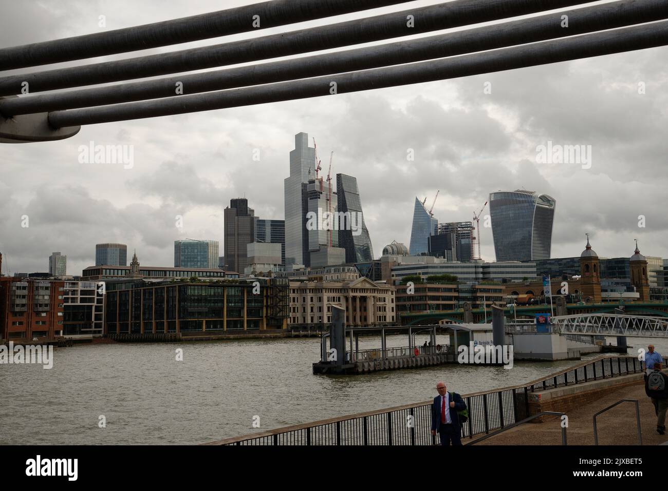 The City of London from the Millennium Bridge. The struts of the bridge framing the view of the City on a grey day. Stock Photo