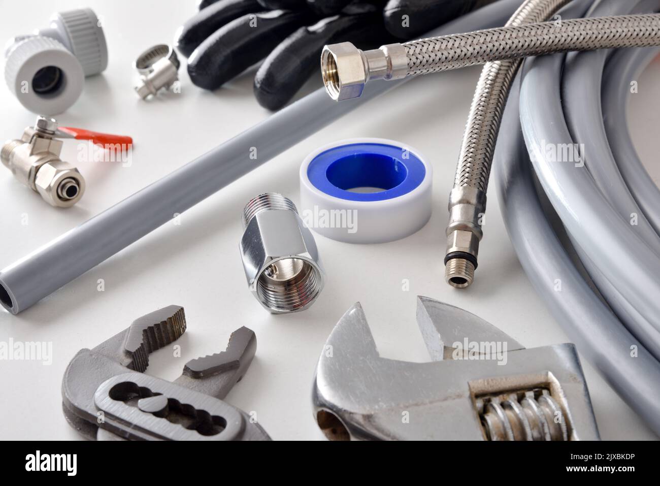 Group of plumbing materials and tools on white workbench. Elevated view