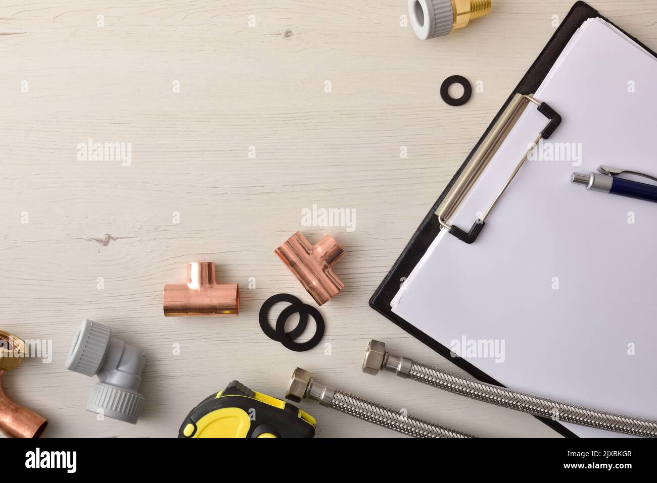 Plumbing material inventory and sale concept with notepad and material on a white wooden table. Top view. Horizontal composition. Stock Photo