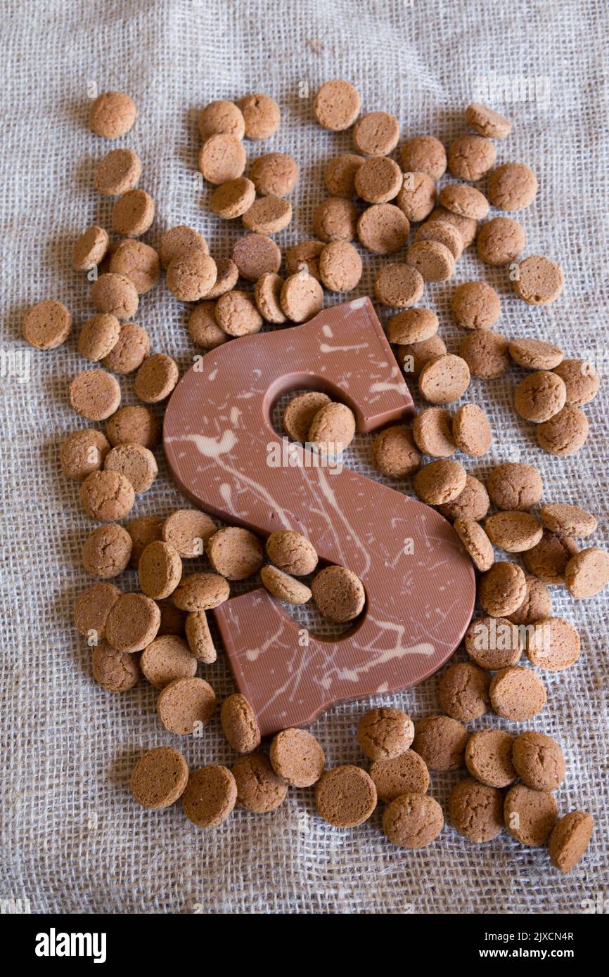 Dutch Sinterklaas tradition: A chocolate letter and candy called Pepernoten on a jute background. Stock Photo