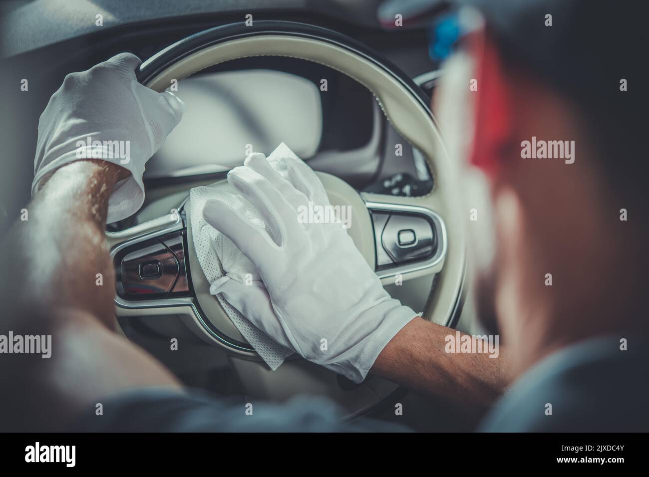 Closeup of Leather Steering Wheel in Modern Vehicle Being Cleaned by Professional Auto Detailer with the Use of Special Fluid-Saturated Wipes. Profess Stock Photo