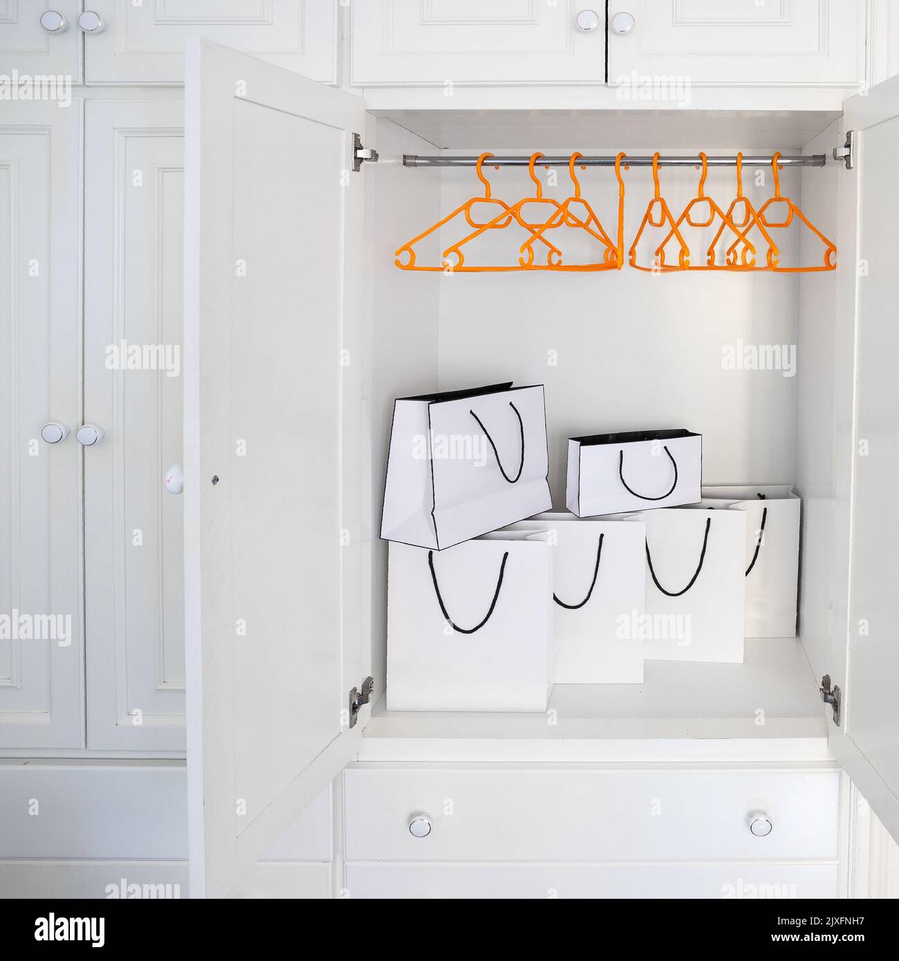 White shopping bags in empty wardrobe with hangers without clothes