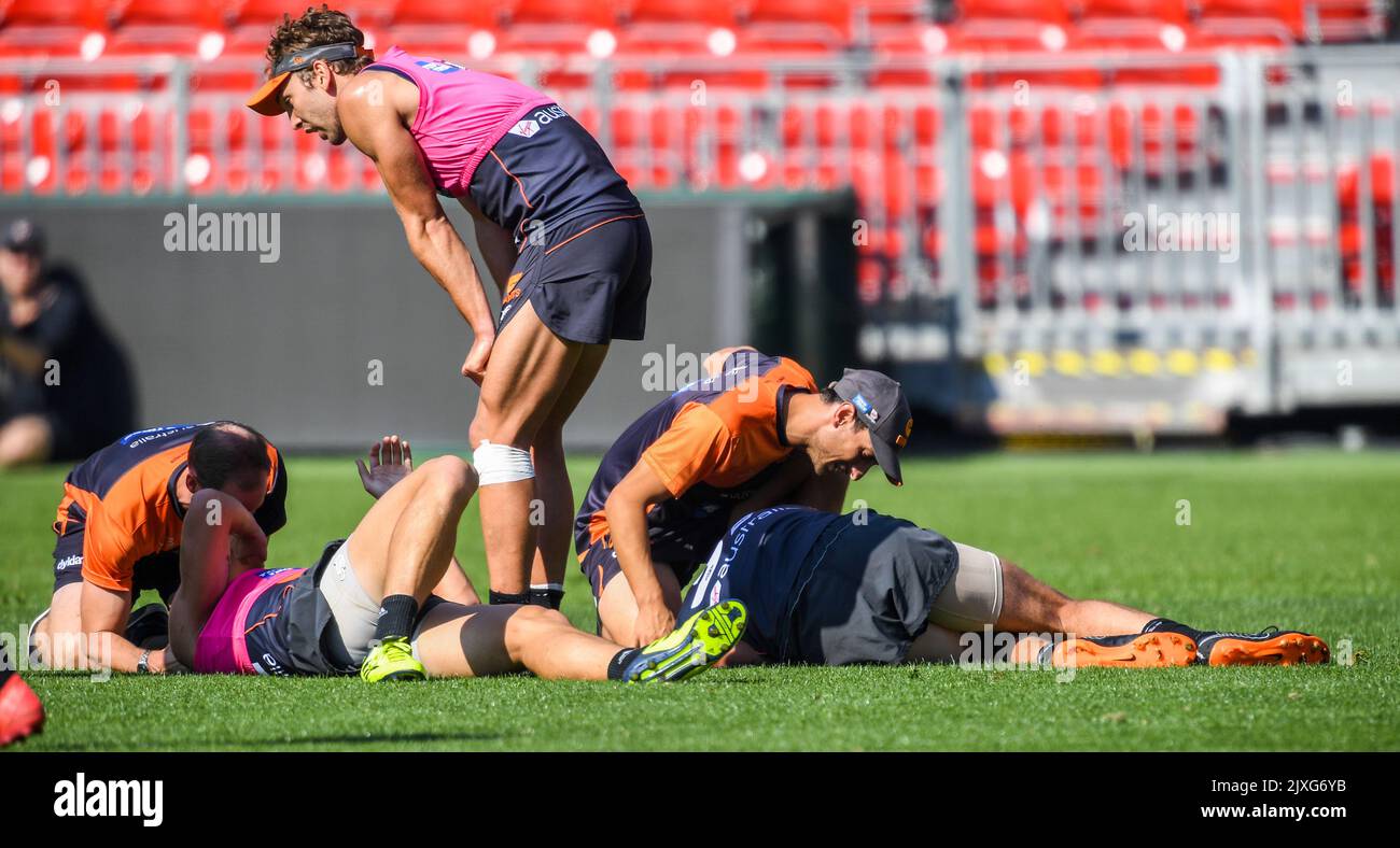 GWS defender Jake Stein (left) and ruckman Rory Lobb are treated by ...