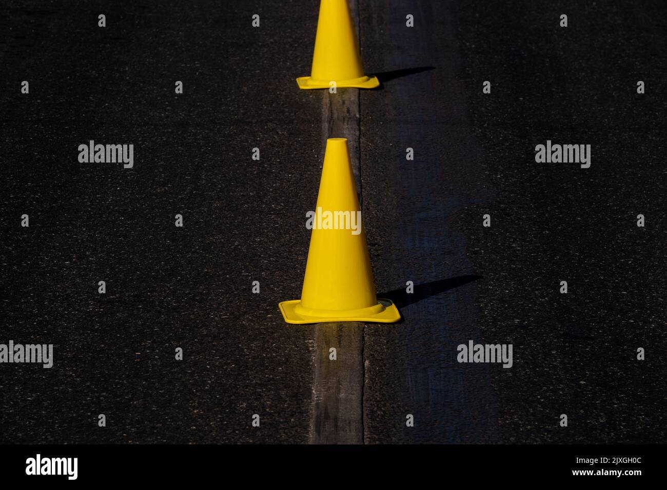 bright yellow safety cones on dark asphalt Stock Photo Alamy