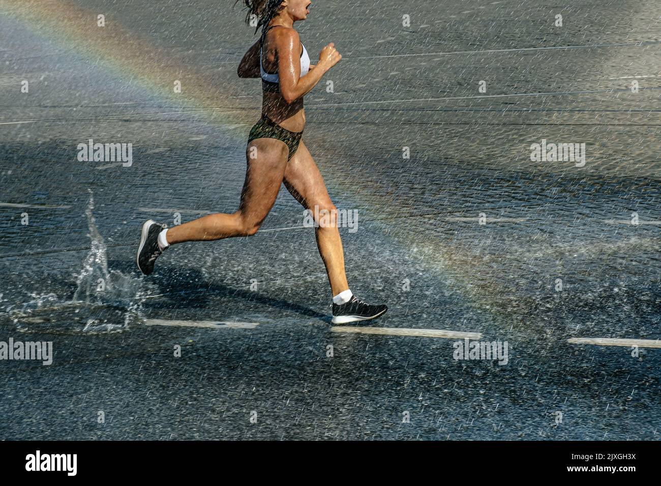 female runner run in water spray and rainbow Stock Photo