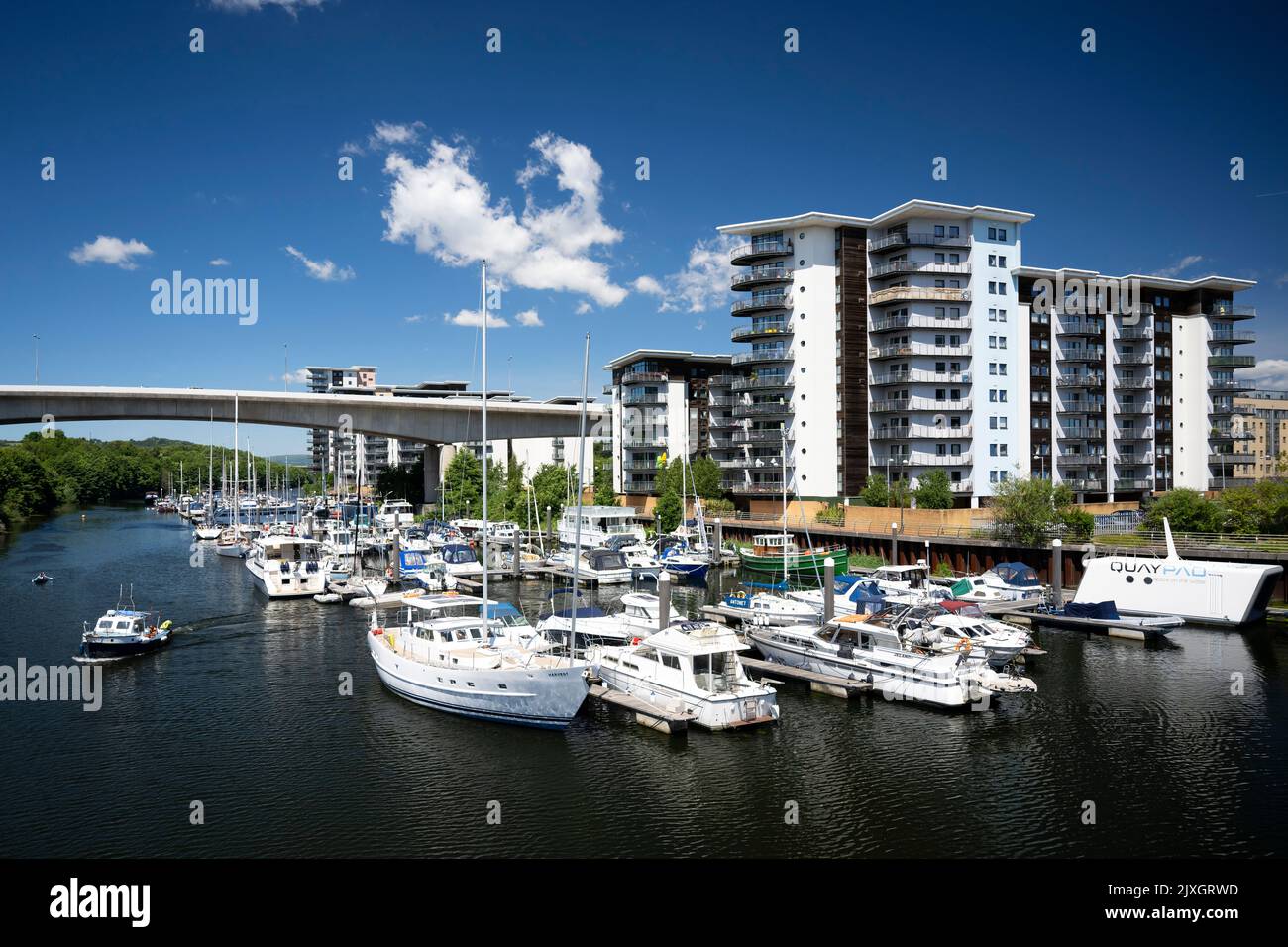 Boats against a blue sky near the Atlantic Wharf flats in the River Ely in Cardiff, Wales, United Kingdom. Stock Photo