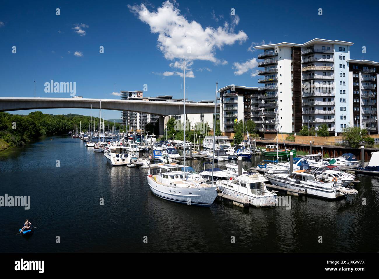 Boats against a blue sky near the Atlantic Wharf flats in the River Ely in Cardiff, Wales, United Kingdom. Stock Photo