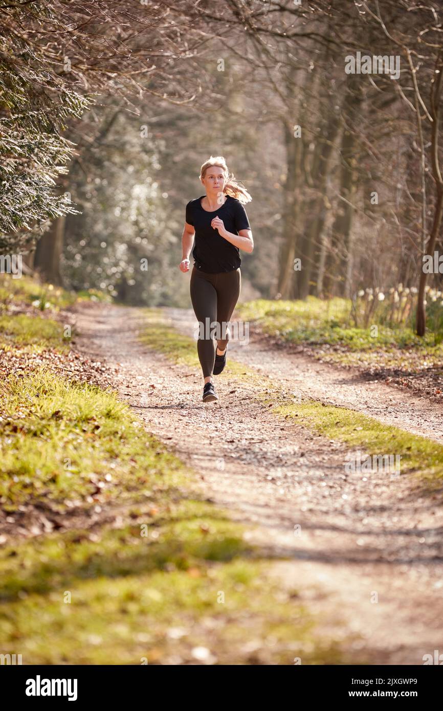 Young Woman Running In Autumn Countryside To Improve Mental Health During Health Lockdown Stock Photo