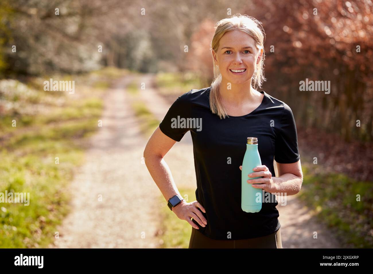 Portrait Of Woman With Water Bottle In Autumn Countryside On Run To Improve Mental Health Stock Photo