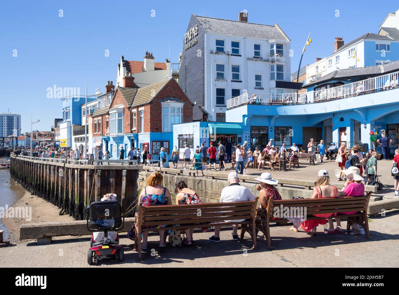 Bridlington old town marina and Bridlington Harbour at low tide with tourists sat enjoying the sunshine East Riding of Yorkshire England UK GB Europe Stock Photo