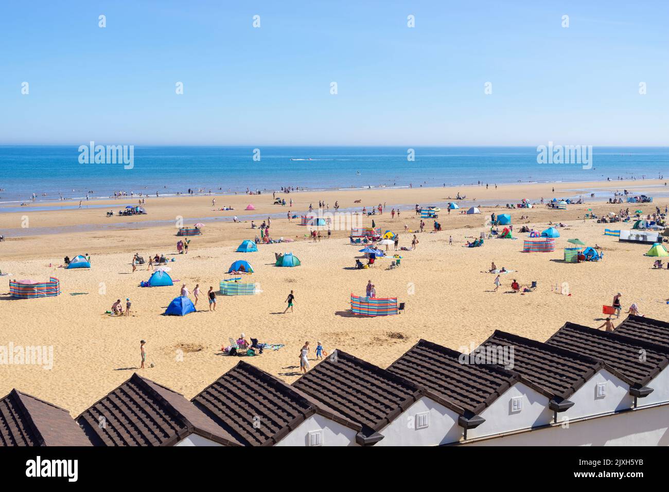 Bridlington South Beach beach huts tourists holidaymakers and people sunbathing on the beach Bridlington East Riding of Yorkshire England UK GB Europe Stock Photo