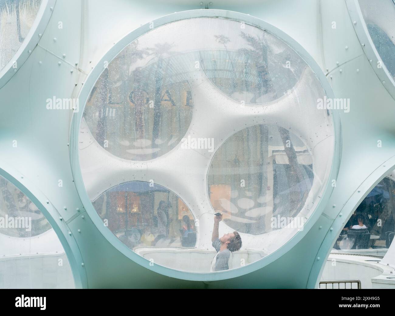 Young man takes a picture in a futuristic glass capsule Stock Photo