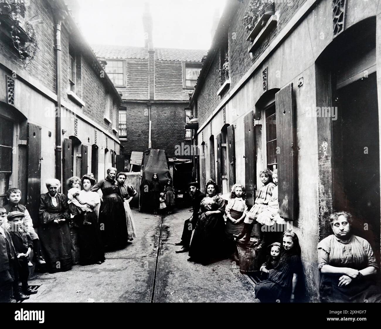 Photograph taken of groups of people standing within an alley in Providence Place, Stepney. Dated 20th Century Stock Photo
