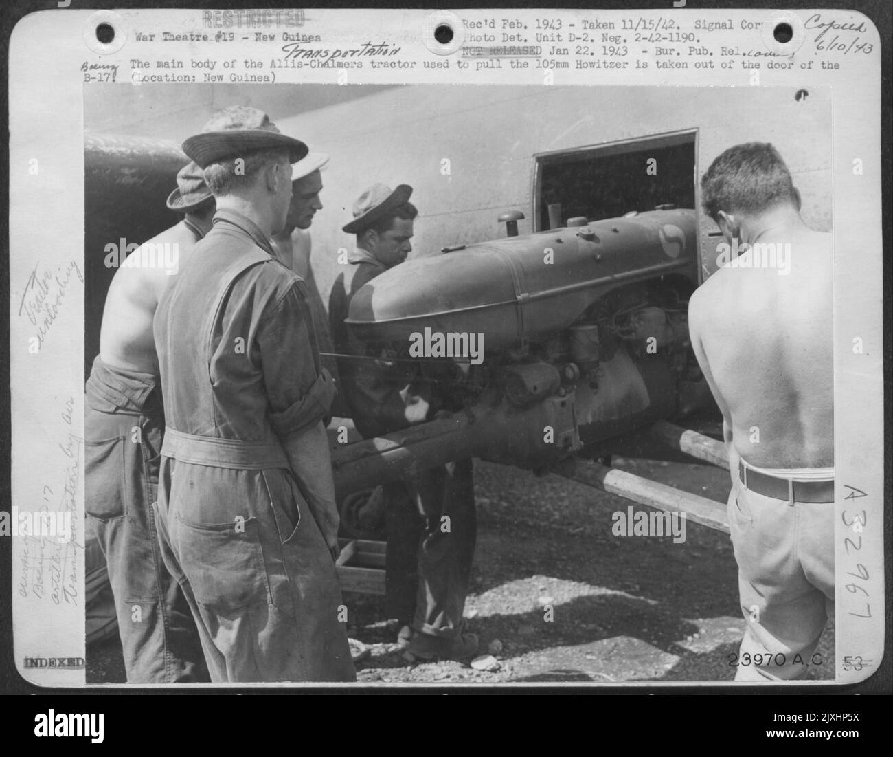 The main body of the Allis-Chalmers tractor used to pull the 105mm Howitzer is taken out of the door of the B-17. (Location: New Guinea) Stock Photo