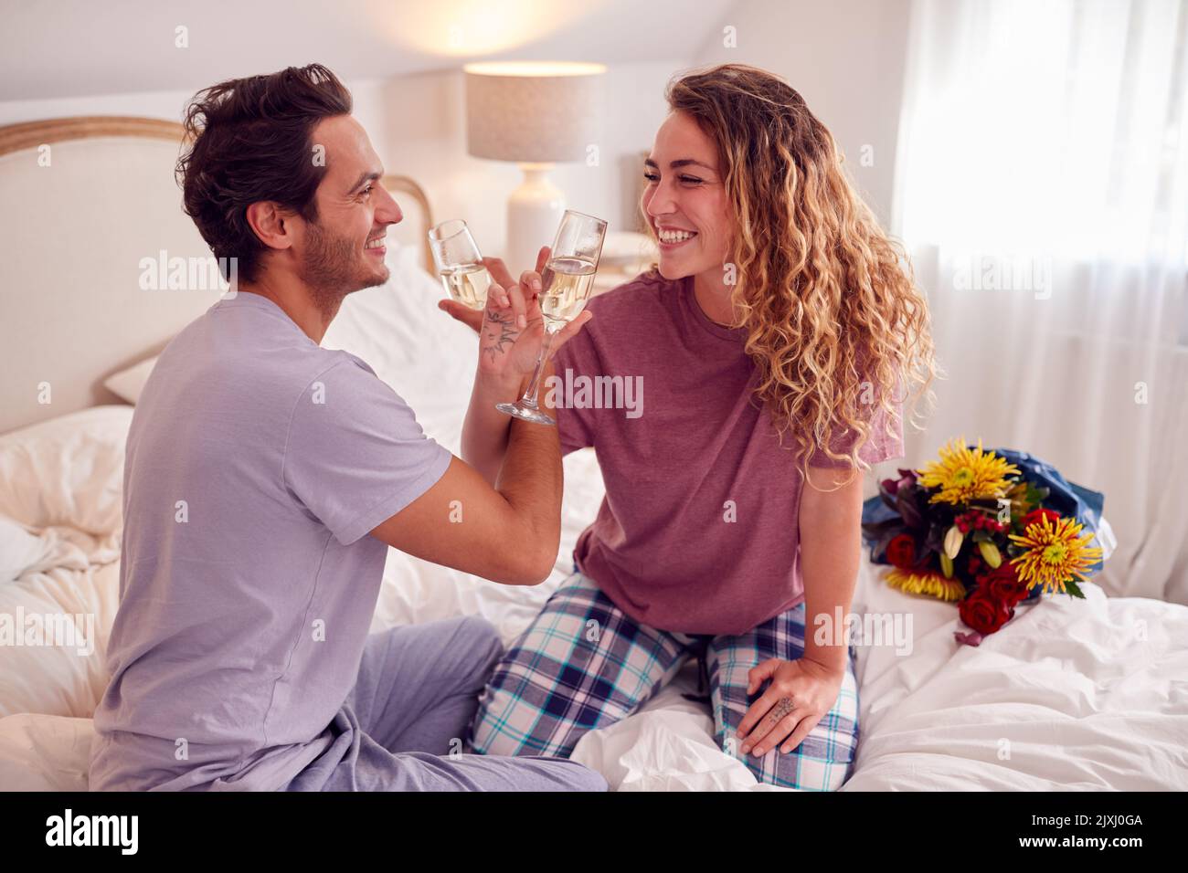 Loving Couple Wearing Pyjamas In Bed At Home Celebrating Birthday Or