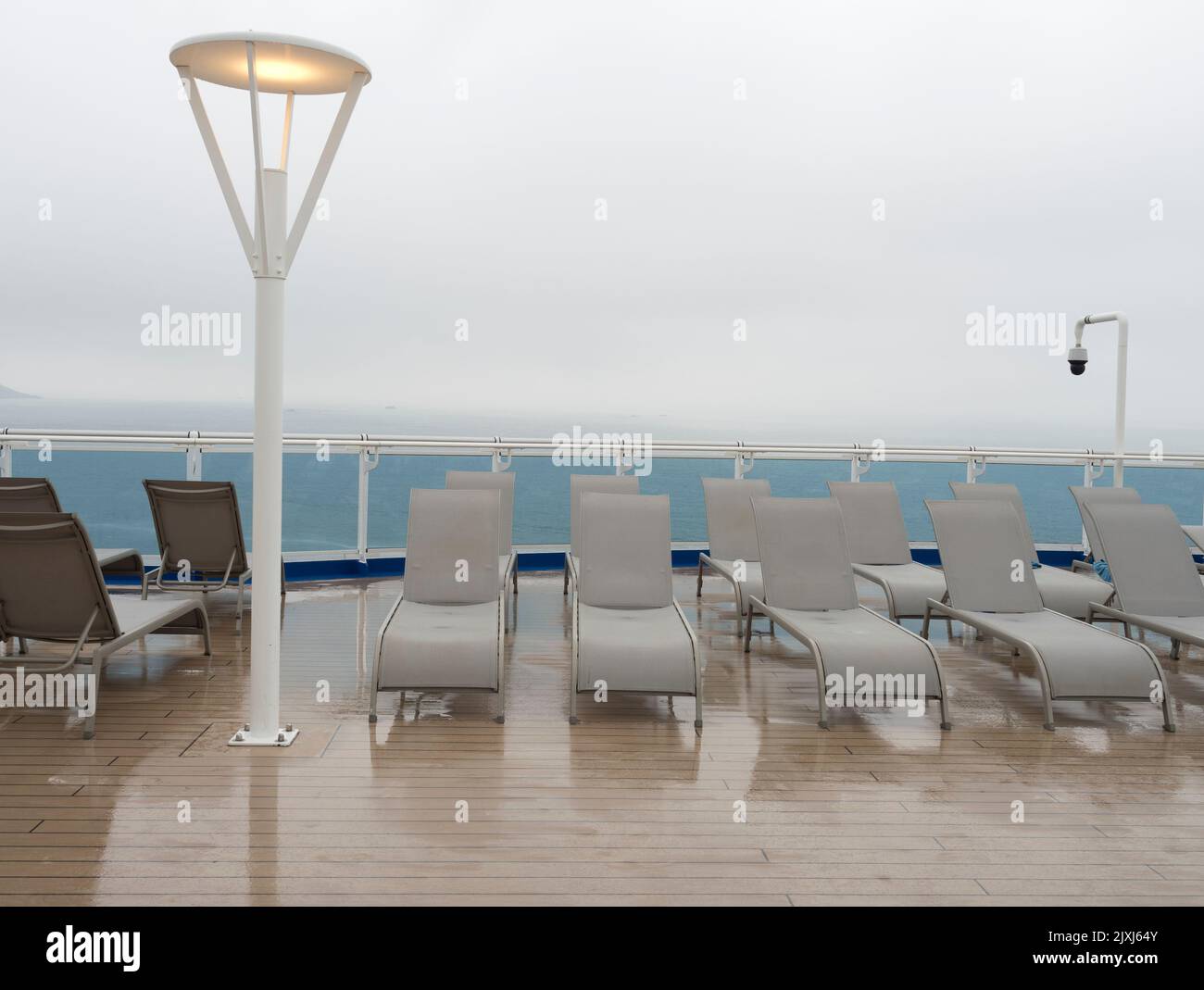 Surreal and paradoxical scene - wet afternoon on the sun deck  of a cruise liner in the North Sea. It is spookily deserted, with a grey, featureless s Stock Photo