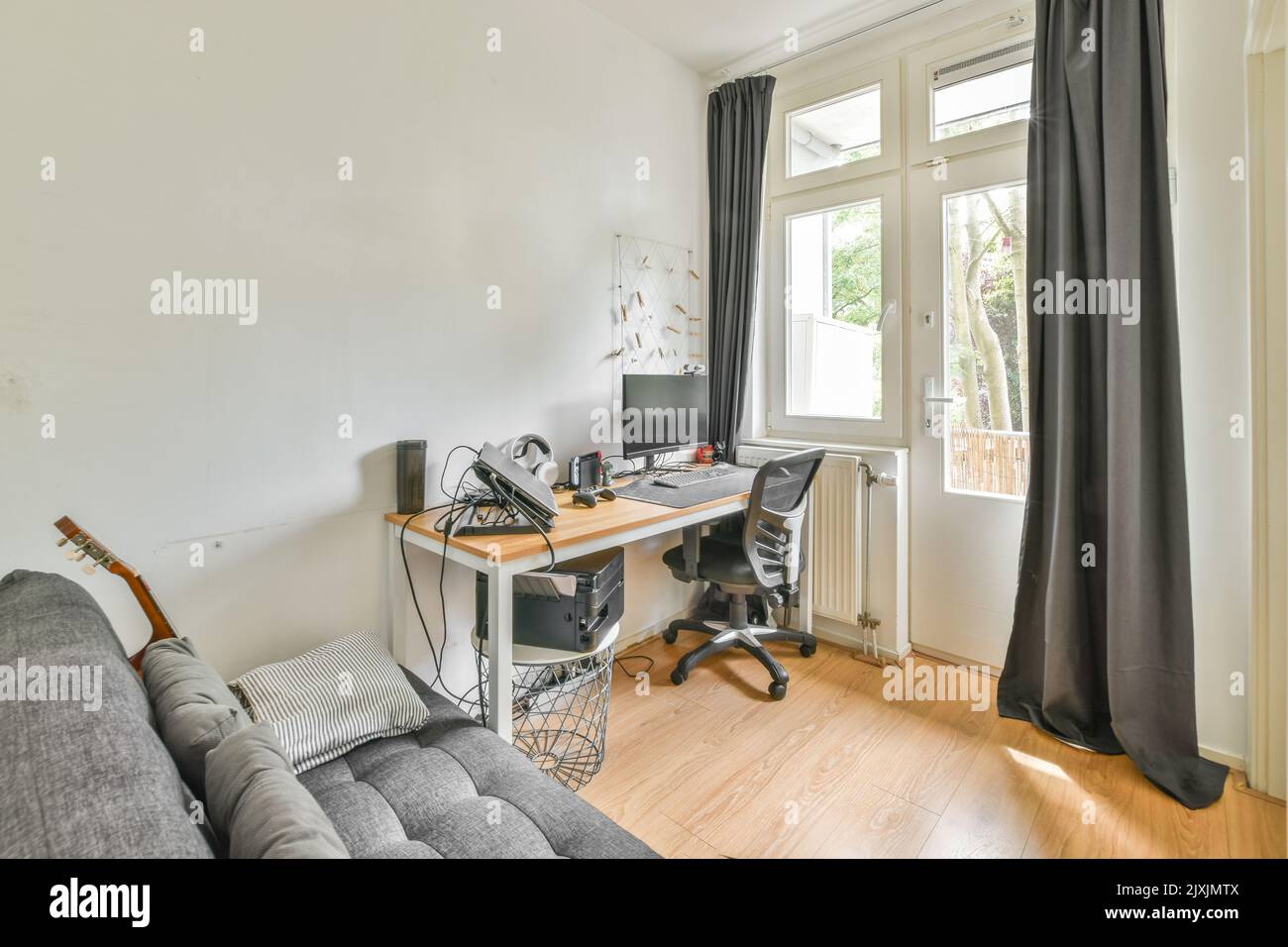Comfortable sofa placed near table with computer monitors in contemporary flat Stock Photo