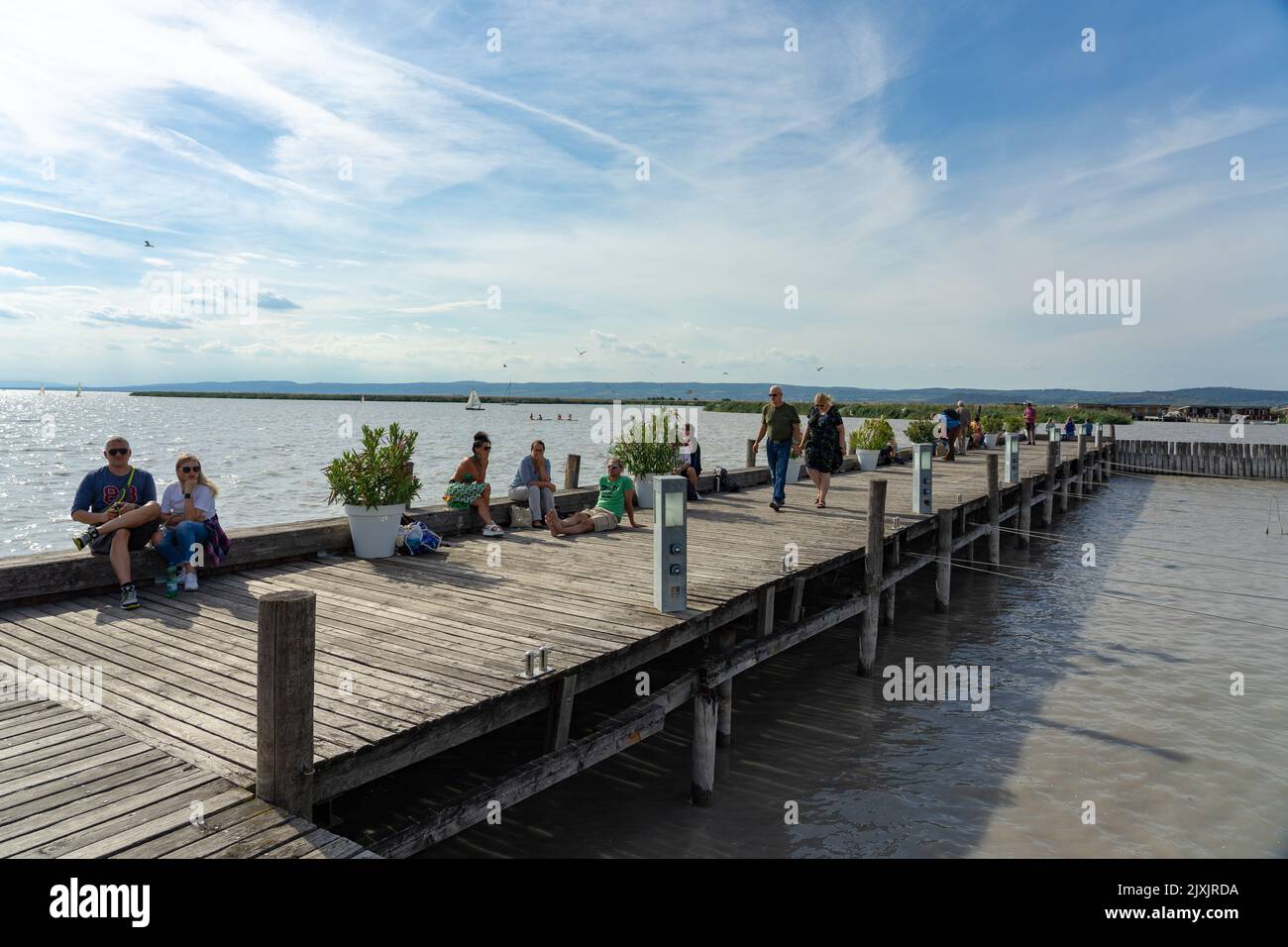 Neusiedl am See, Austria - 05.09.2022 : People relaxing on a pier next to Neusiedlersee on a sunny day Stock Photo