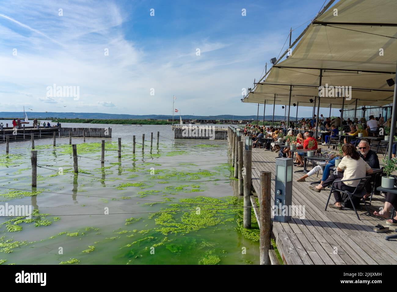 Neusiedl am See, Austria - 05.09.2022 : People relaxing on a pier next to Neusiedlersee on a sunny day Stock Photo