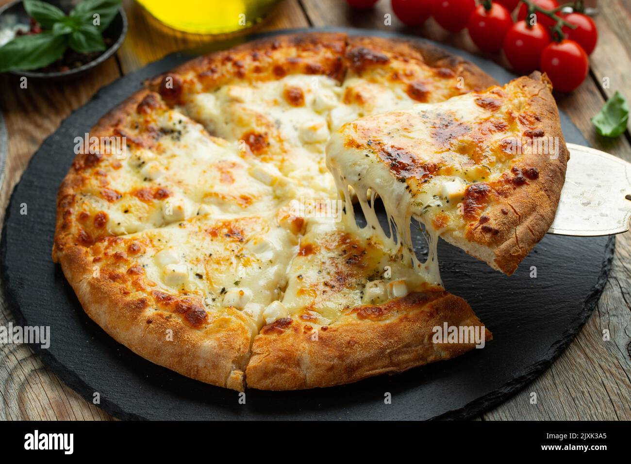 A slice of hot Italian pizza with stretching cheese. Pizza four cheeses with basil. Stock Photo