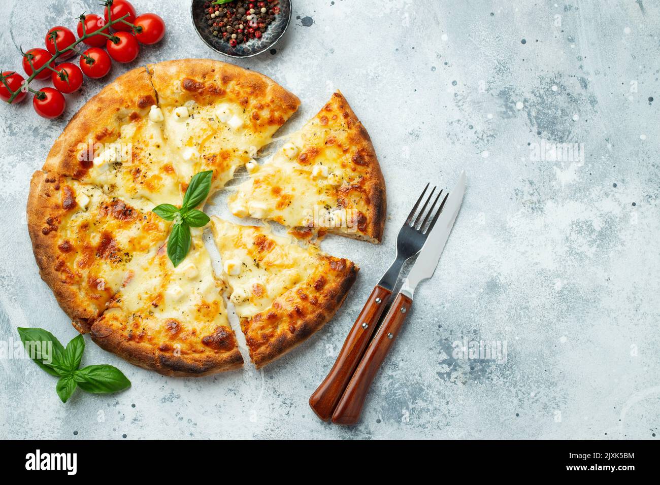 Italian pizza four cheeses with stretching cheese and basil on a light