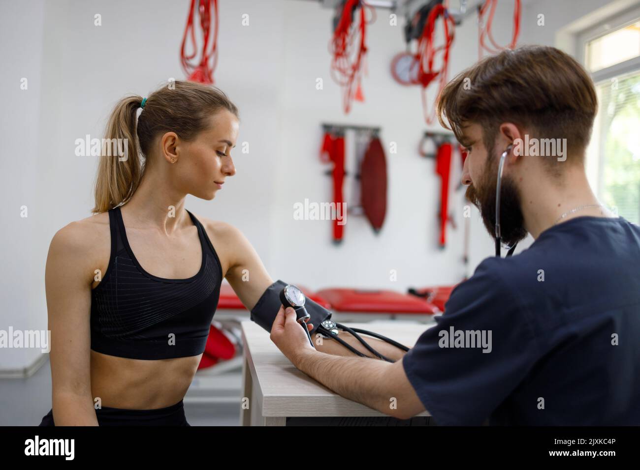 Athletic woman undergoing medical examination in rehabilitation clinic. Doctor measures the